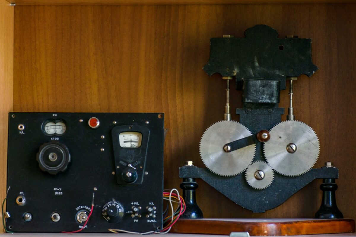 Close-up of vintage electrical equipment with metal gears in a wooden setting.