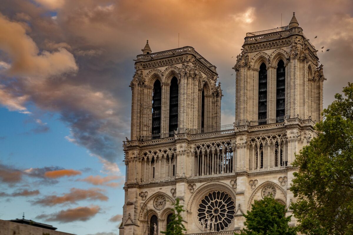 The iconic Notre-Dame Cathedral captured at sunset with dramatic skies in Paris.