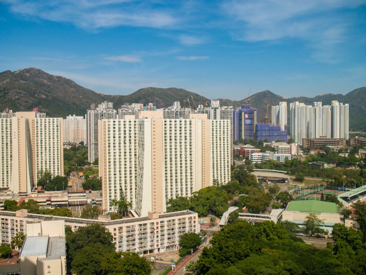 A scenic view of high-rise residential buildings in Hong Kong with lush greenery and mountains.